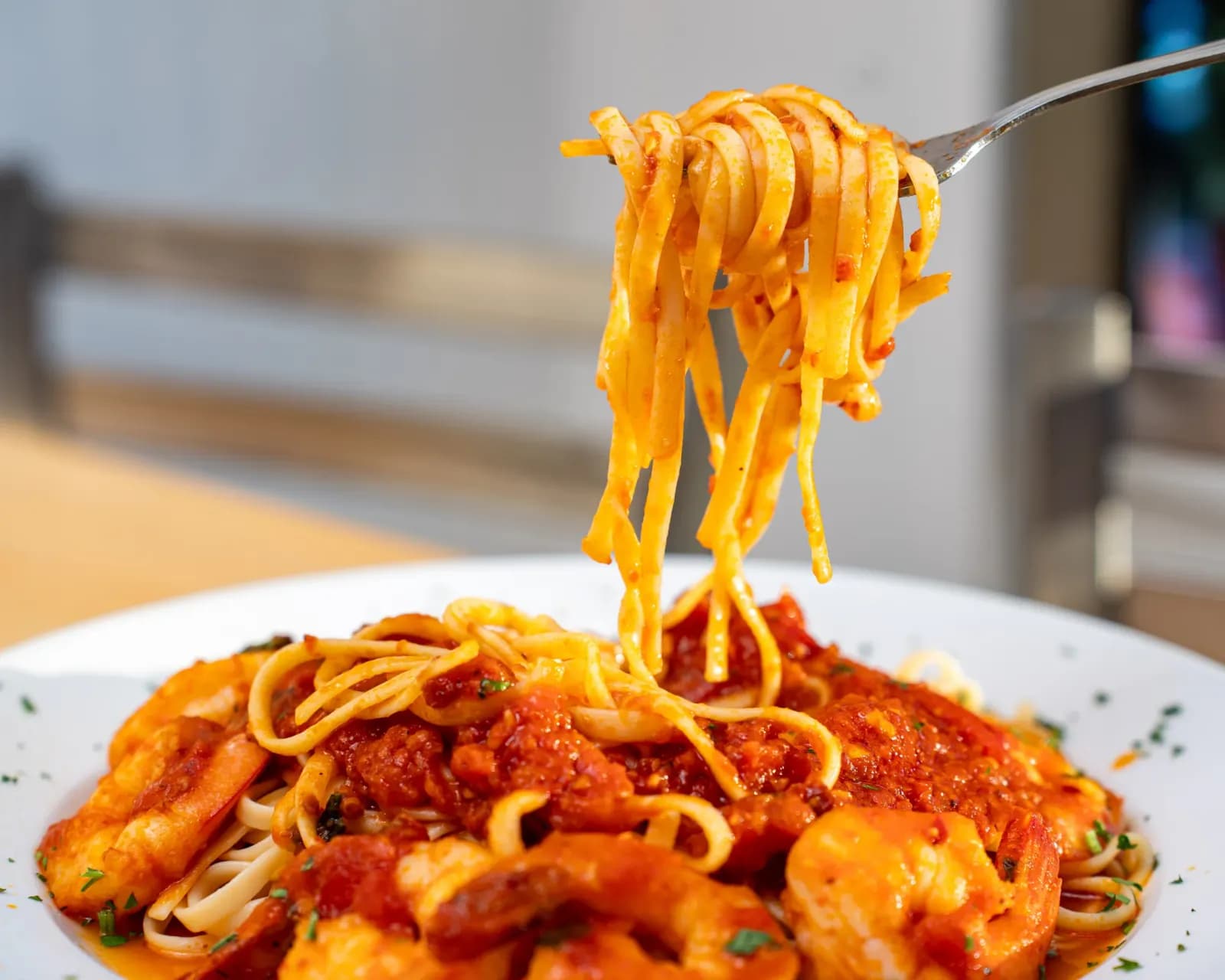 Forkful of linguine lifted from a plate of shrimp fra diavolo